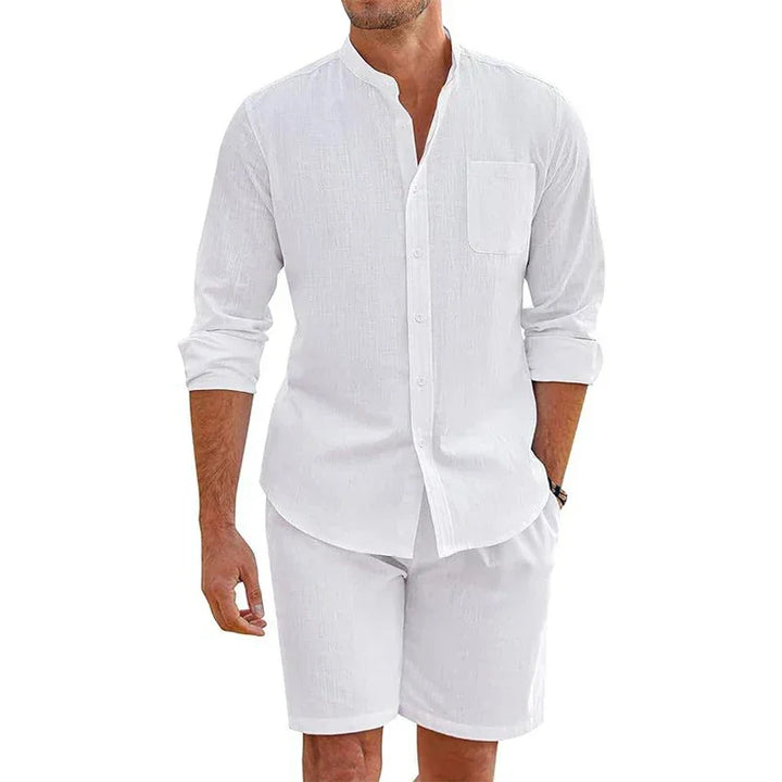 A man wearing a vintage stand collar shirt with a mandarin neckline and matching baggy shorts, standing with one hand in his pocket against a plain background.