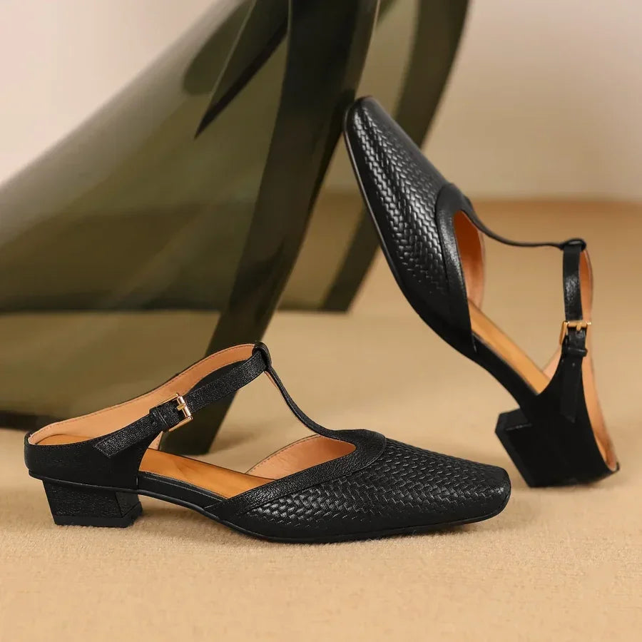 Rovelli black woven leather block heel sandals with T-strap and gold buckle on beige background
