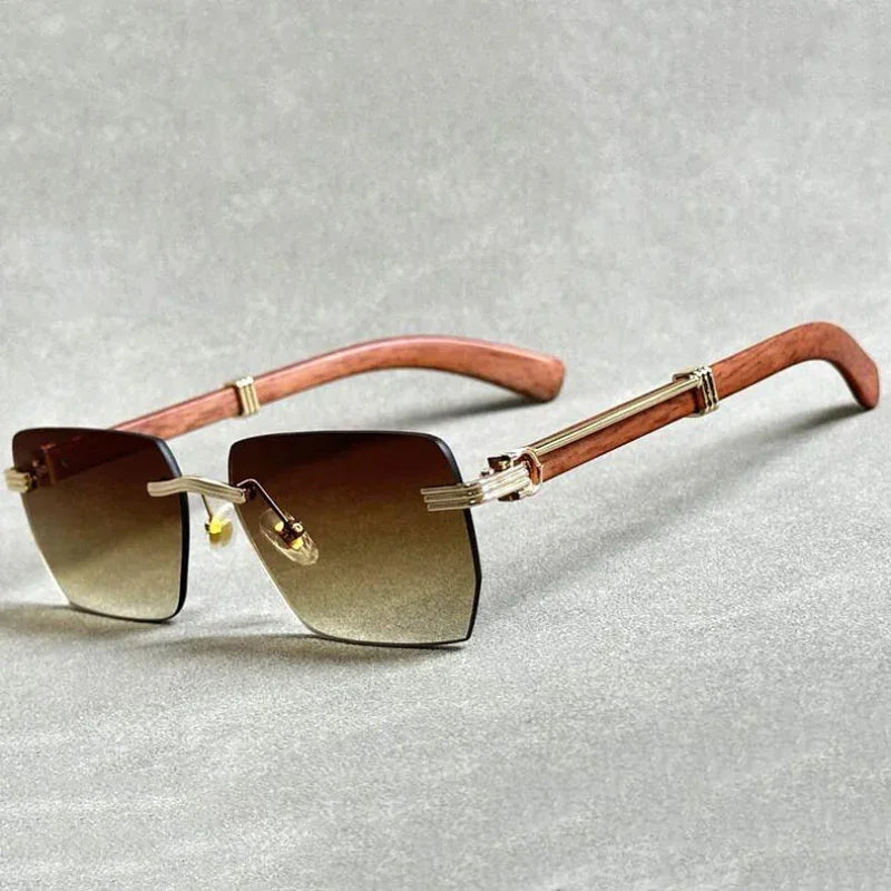 Rectangular rimless sunglasses with gradient lenses, gold accents, and stylish wooden temples, displayed on a light gray surface.