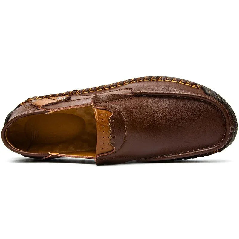 A brown leather loafer shown from a top view, featuring traditional craftsmanship with visible hand-stitched details along the edges and a soft, tan interior.