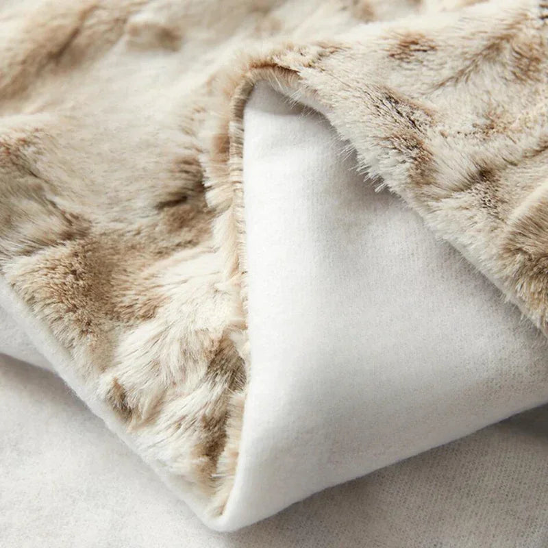 A close-up of an ultra-soft luxurious blanket in light brown faux fur with a white, smooth inner lining, highlighting its plush, textured surface and cozy material.