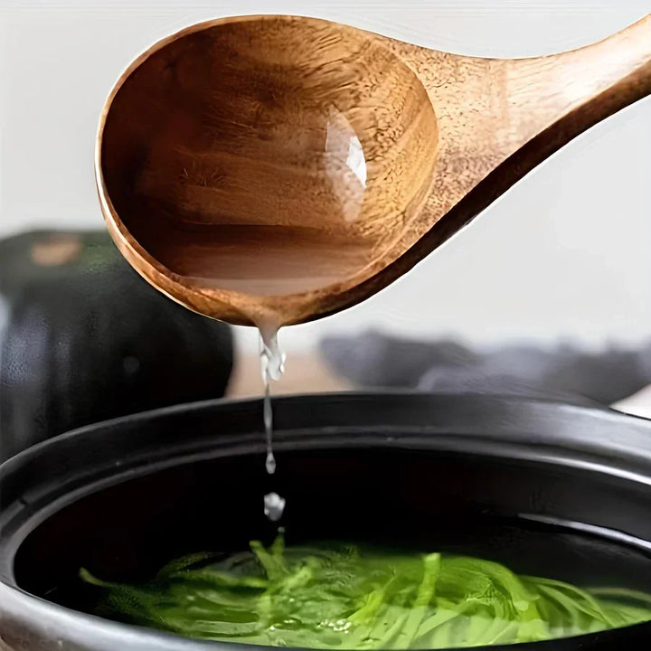 Teak kitchen ladle pouring liquid into a black pot with vegetables, Rovelli cookware