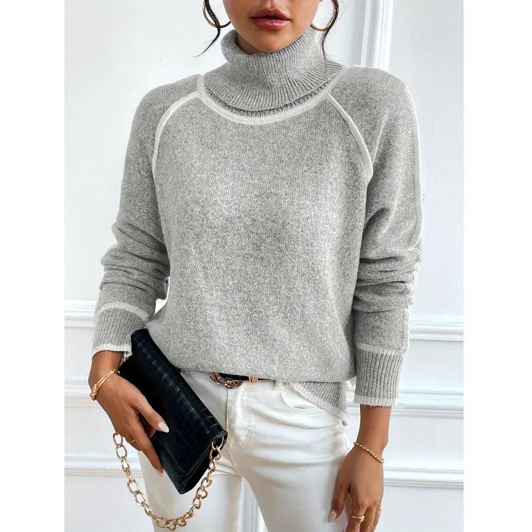 Woman in grey turtleneck sweater and white jeans holding black purse, Rovelli fashion