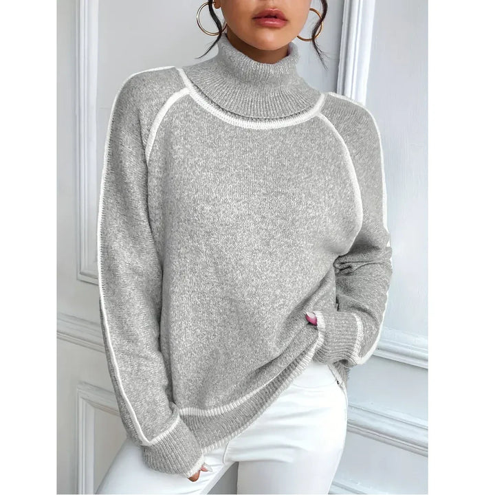 Woman wearing a grey turtleneck sweater with white trim, styled with white pants, Rovelli fashion