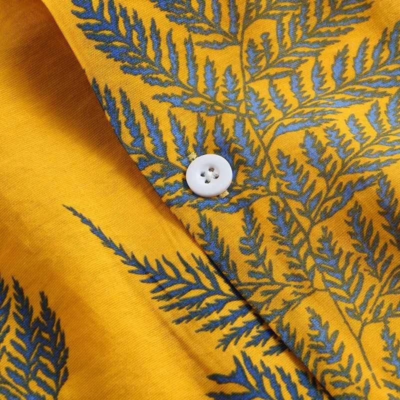 Close-up of a yellow cotton shirt featuring blue fern leaf patterns and a single white button, showcasing a classic design perfect for a casual brunch.