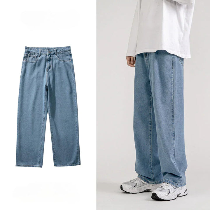 Light blue mens baggy jeans with a wide-leg design shown alone on the left and worn by a person on the right, styled with a loose white long-sleeve shirt and white sneakers for a classic Korean fashion look against a neutral background.