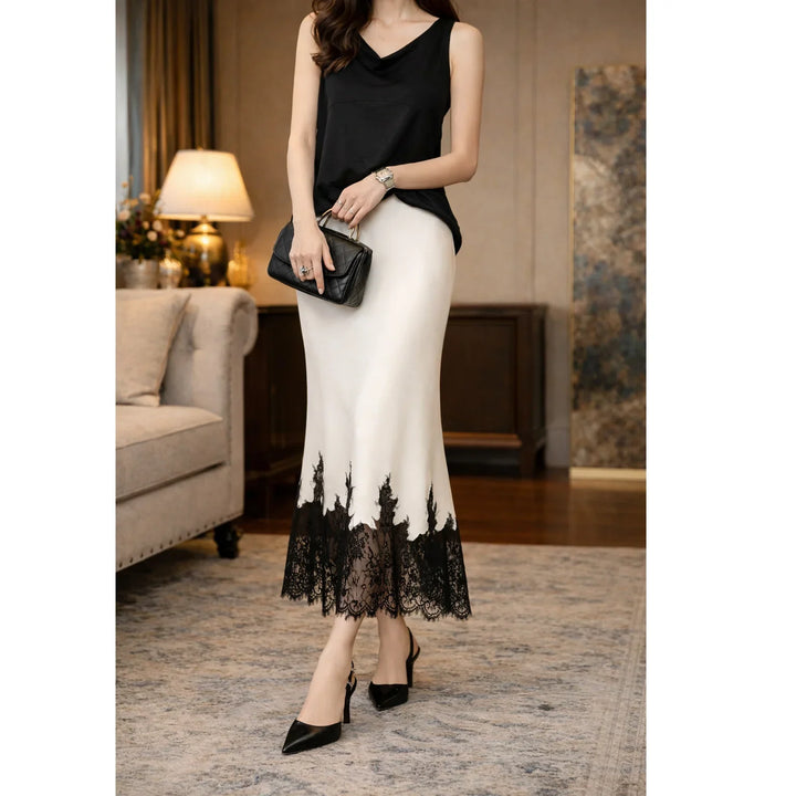 Elegant woman in black top and white skirt with lace detail, holding clutch, Rovelli fashion