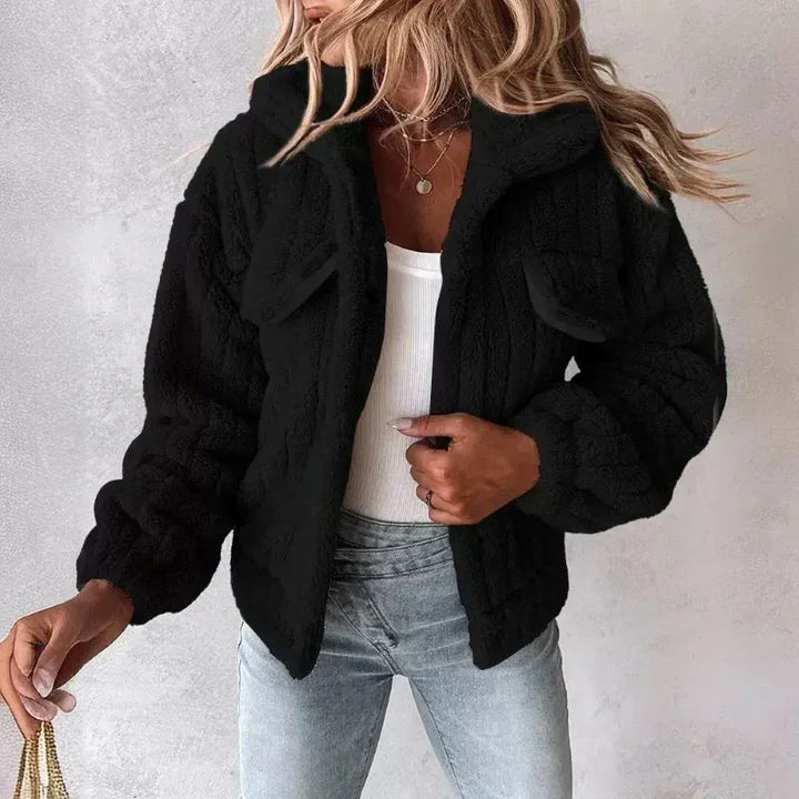 Woman wearing black faux fur jacket from Rovelli, styled with light jeans and white top