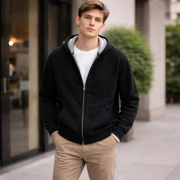 Man wearing black zip-up hoodie and khaki pants outside modern building, Rovelli fashion