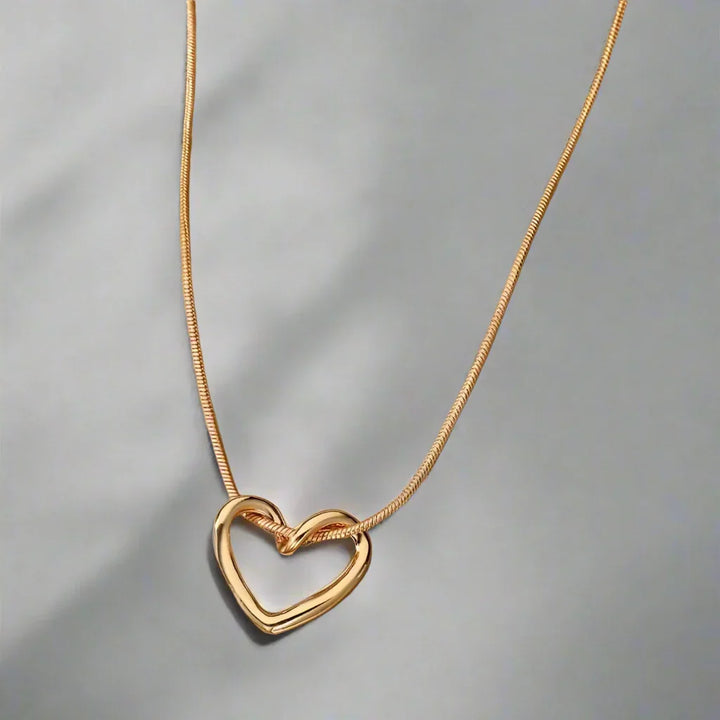 Rovelli gold heart pendant necklace on a sleek snake chain, elegant jewelry on gray background