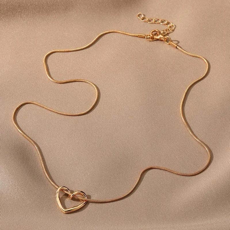 Rovelli gold heart pendant necklace on soft beige fabric background