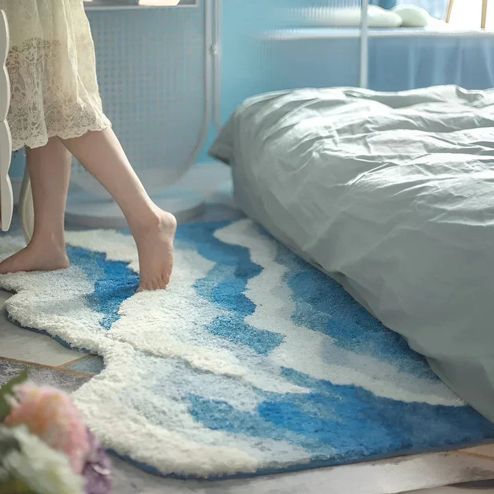 Rovelli bedroom with soft wave-pattern blue and white rug beside a bed, cozy decor