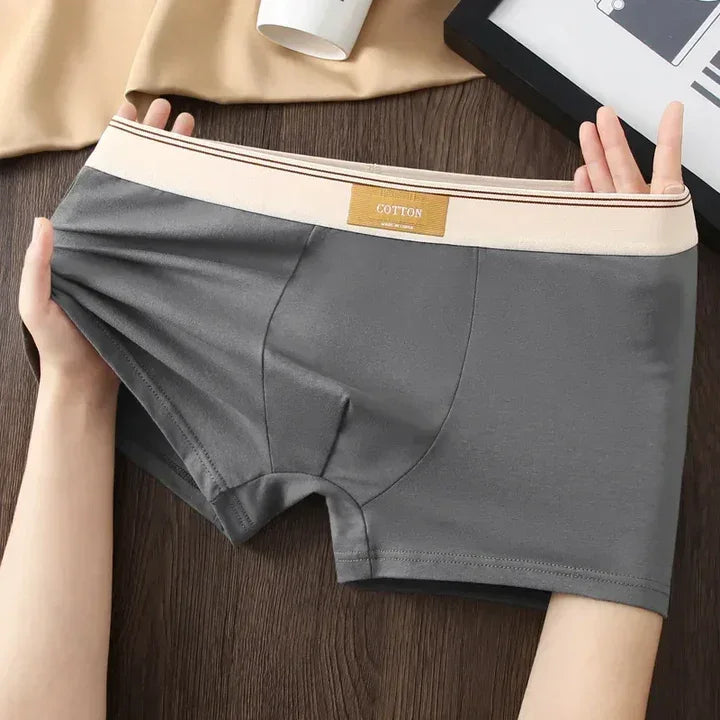 Stretchy gray cotton men's boxer briefs with beige waistband, displayed on wooden table