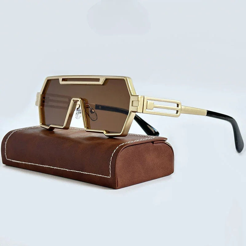 Futuristic gold-rimmed steampunk sunglasses with brown rectangular lenses, thick square frames, and black temple tips, resting on a brown leather case with white stitching.