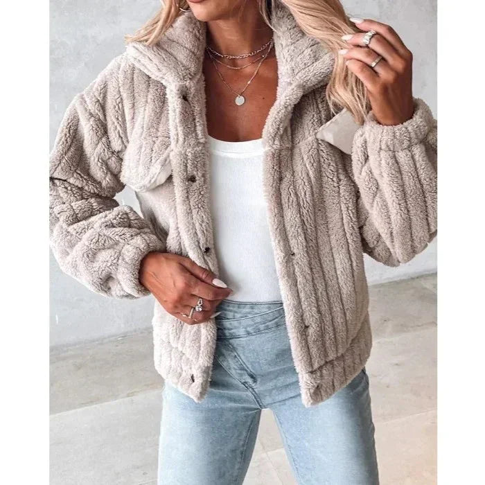 Woman wearing beige faux fur jacket, white top, and light blue jeans from Rovelli