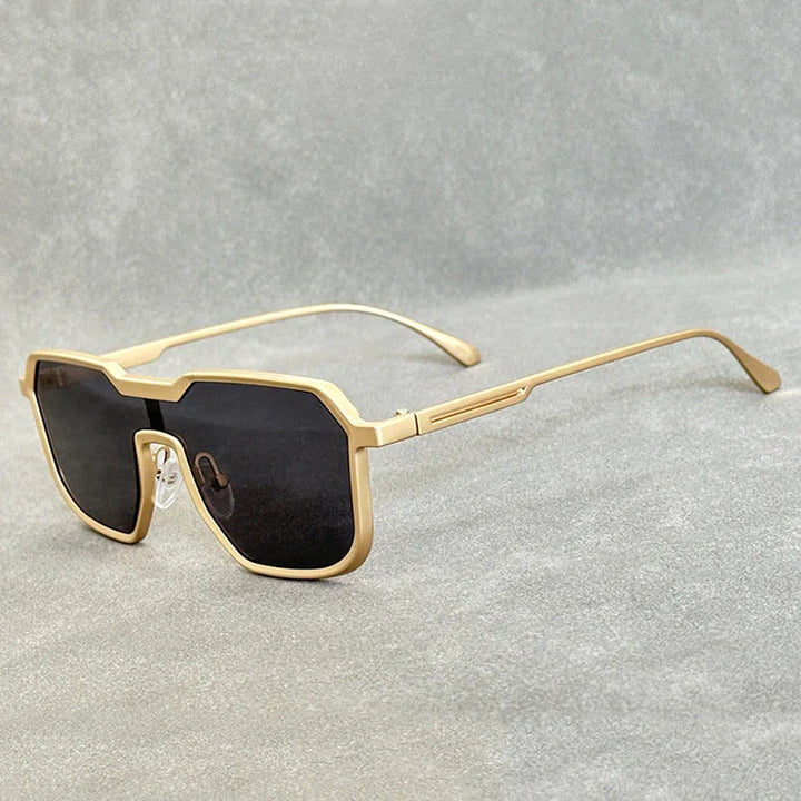 A pair of Steampunk Sunglasses with bold, geometric gold square frames and dark, oversized lenses rests on a gray textured surface.