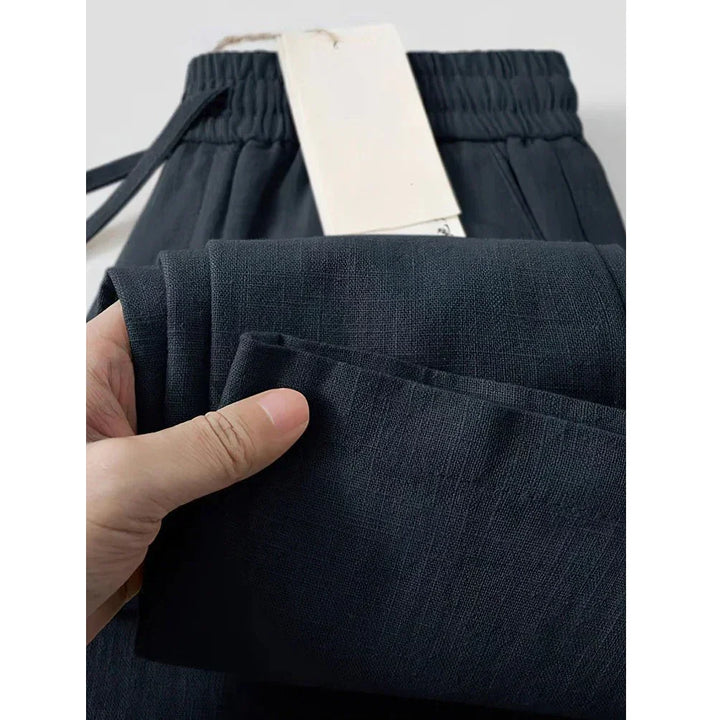 Close-up of hand holding black Rovelli pants with elastic waistband and visible fabric texture
