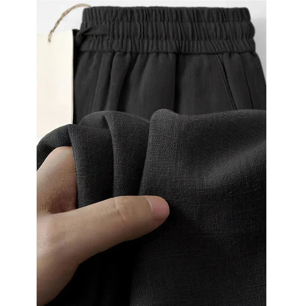 Hand holding soft black elastic waist pants fabric, Rovelli clothing detail