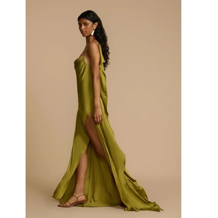 Woman modeling olive green satin Odessa dress by Rovelli with side slit, neutral backdrop