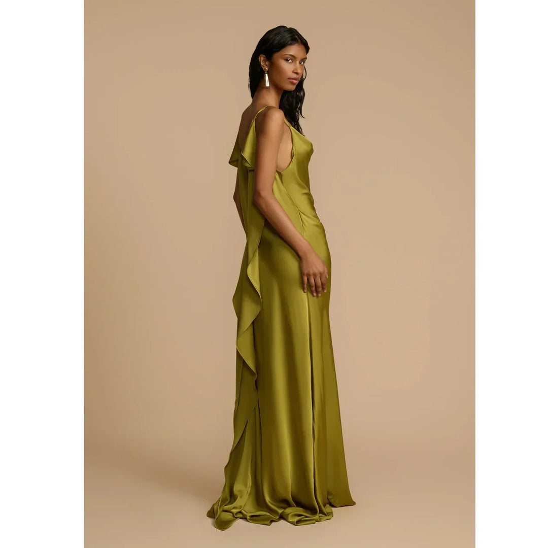 Woman in olive green satin ruffle gown by Rovelli, standing on beige background