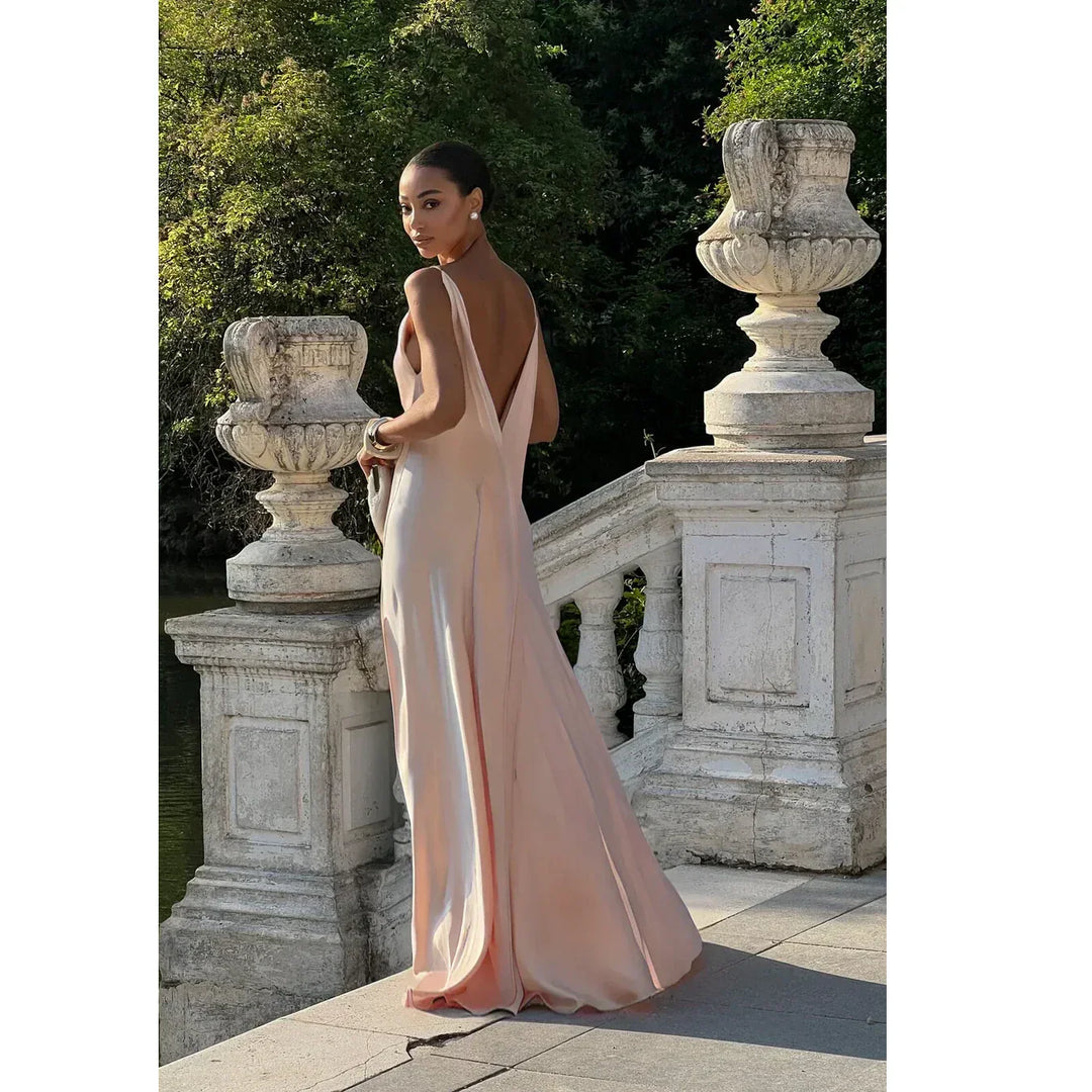 Woman in elegant blush evening gown on stone terrace, Rovelli fashion style, outdoor setting