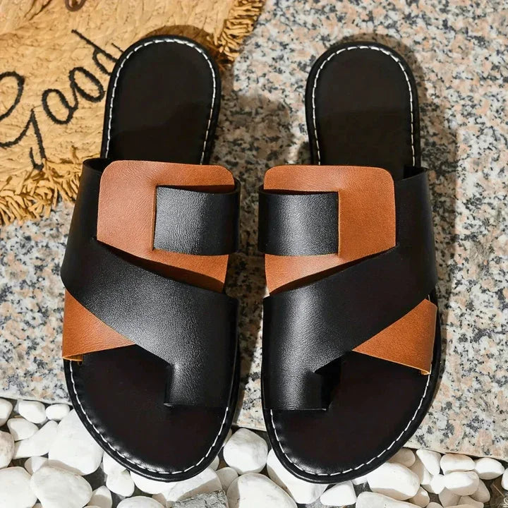 Rovelli two-toned black and brown slip-on slippers on a textured stone surface