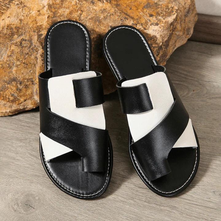 Rovelli two-toned black and white slip-on slippers with crisscross straps on wood floor