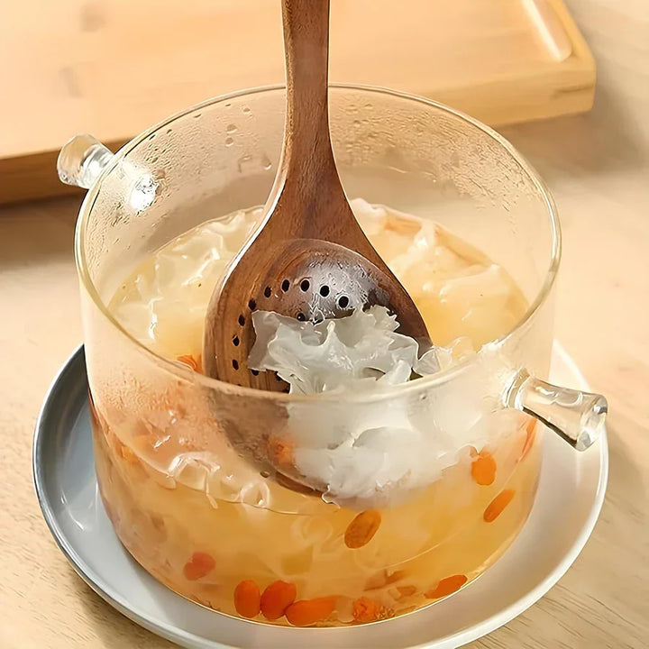 Natural teak wood kitchen utensil stirring soup in clear glass pot on wooden table, Rovelli