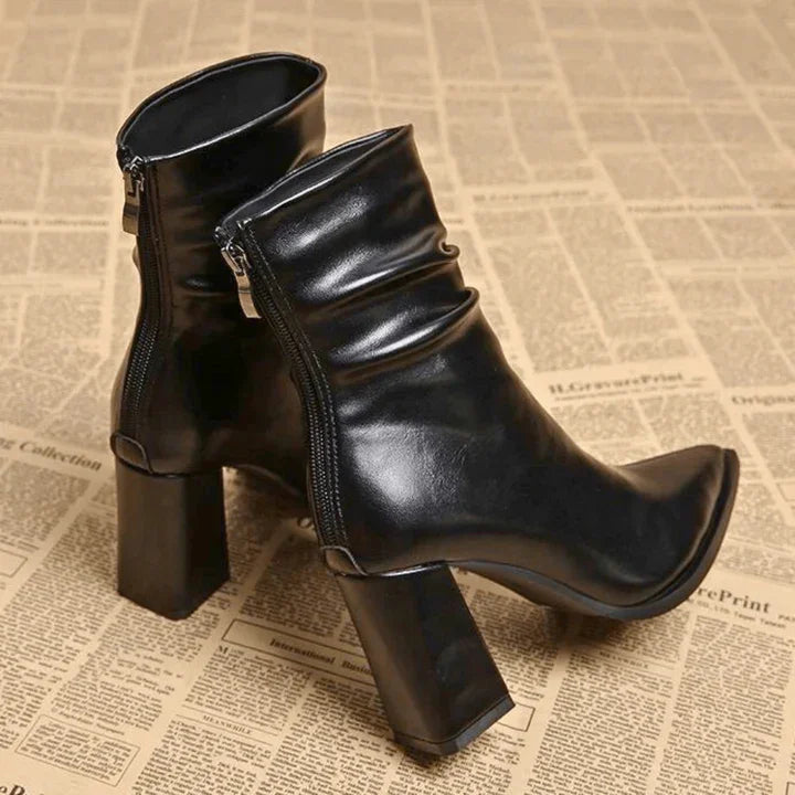 Rovelli black leather block heel ankle boots with side zipper on newspaper background