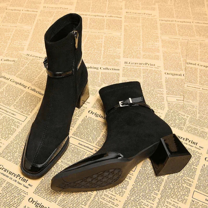 Black suede heeled ankle boots with patent leather details on vintage newspaper background, Rovelli