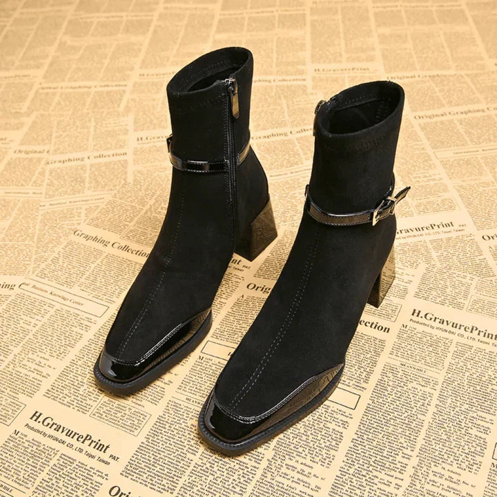Black suede ankle boots with block heels and side zippers on vintage newspaper background, Rovelli