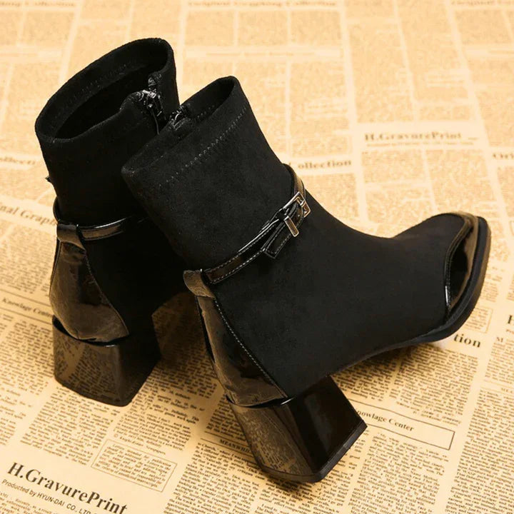 Black suede ankle boots with chunky heels and decorative buckle from Rovelli on newspaper background