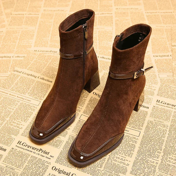 Pair of Rovelli brown suede ankle boots with buckle and side zipper on newspaper background