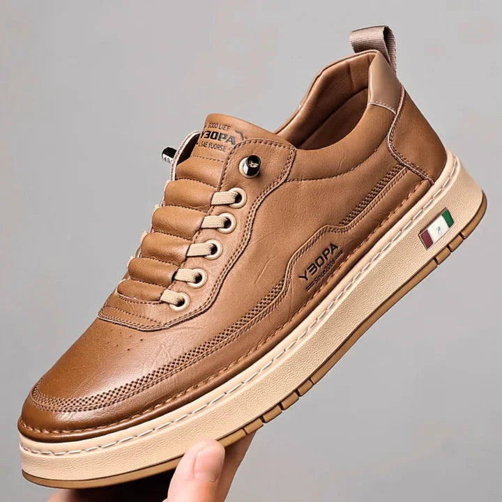 Brown leather Rovelli sneaker with cream sole and Italian flag detail, held in hand.