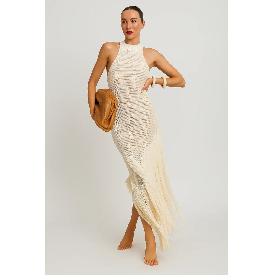 Woman in a white crochet fringe dress holding a tan clutch, Rovelli fashion style