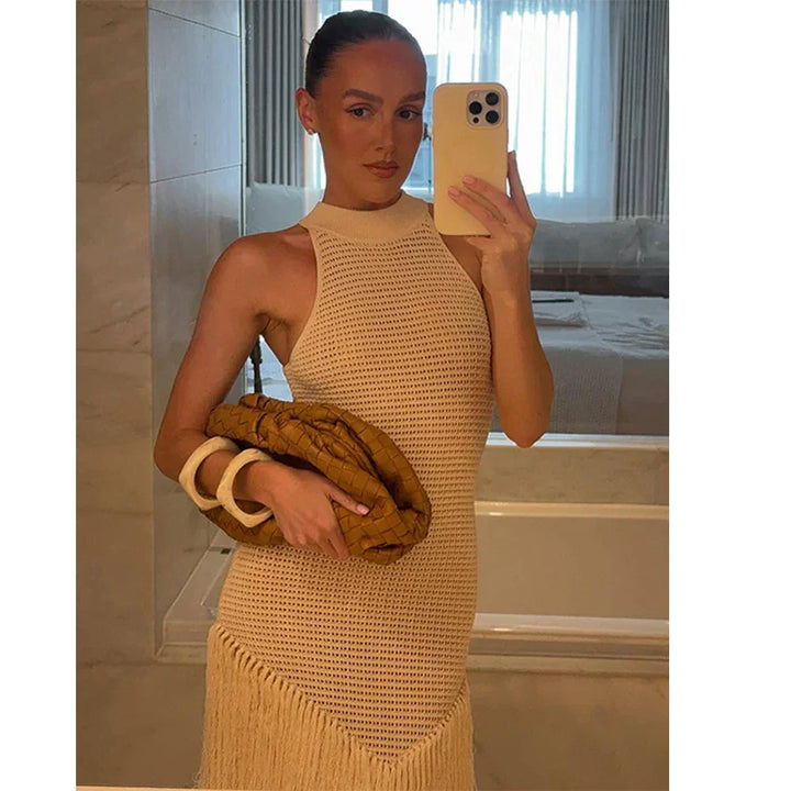 Woman wearing a white crochet dress with fringe, holding a brown clutch, in a modern bedroom mirror selfie.
