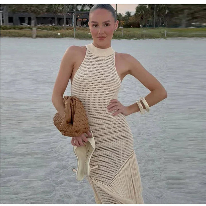 Woman in sleeveless white crochet dress holding tan bag on the beach, Rovelli fashion